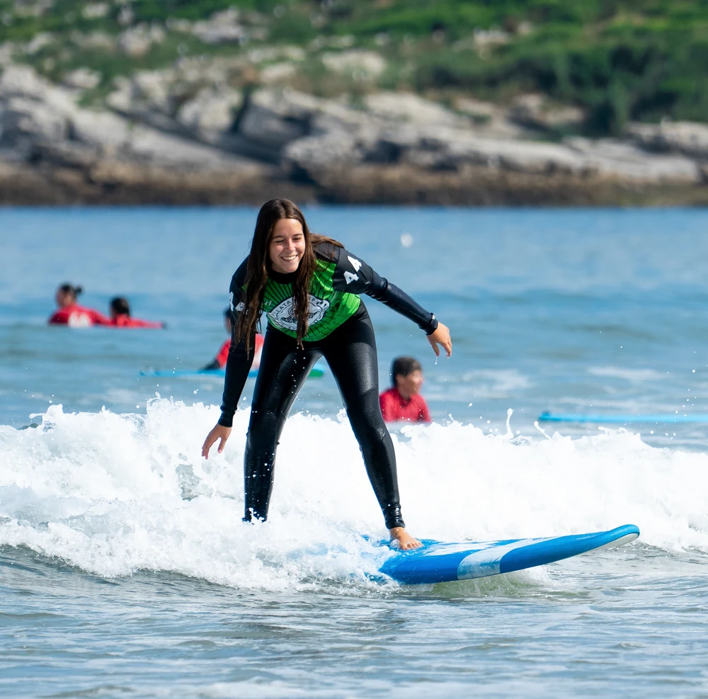 Chica surfeando una ola en la clase de surf del Campus Baloncesto y Surf Cantabria en Somo